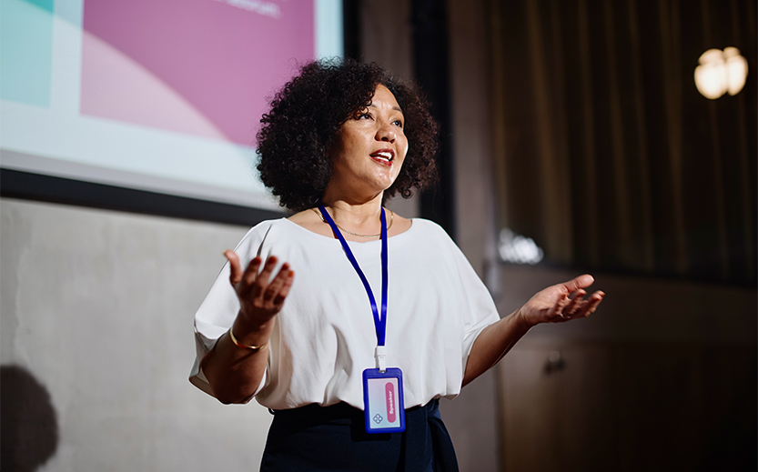 a woman with black curly hair wearing a lanyard and a white shirt
