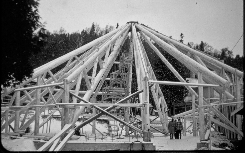 a structure under construction with people standing in front of trees