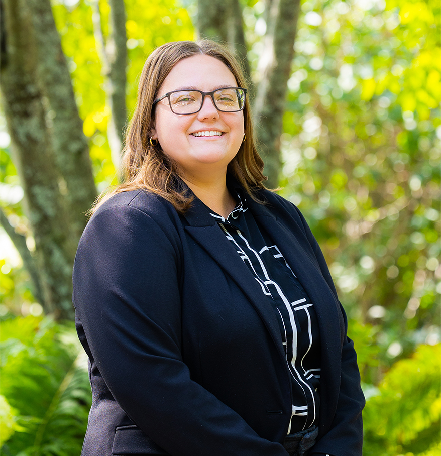 a woman smiling in front of trees