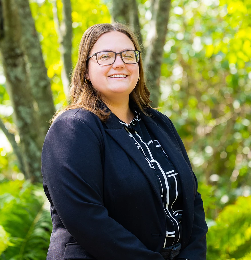 a woman smiling in front of trees