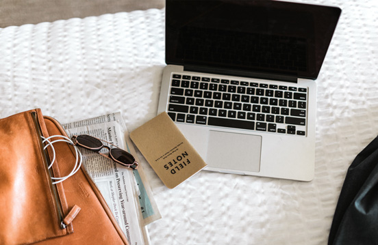 a laptop and sunglasses on a bed