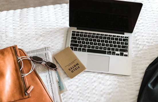 a laptop and sunglasses on a bed