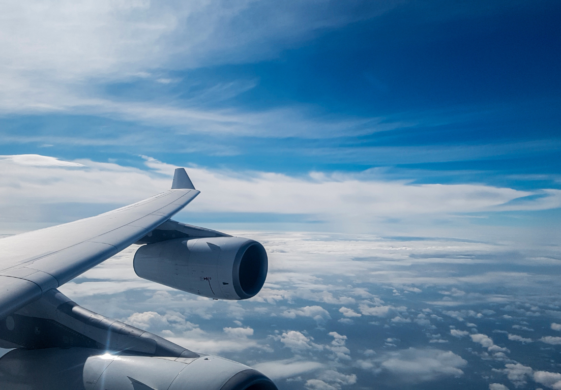 an airplane wing and engine above clouds