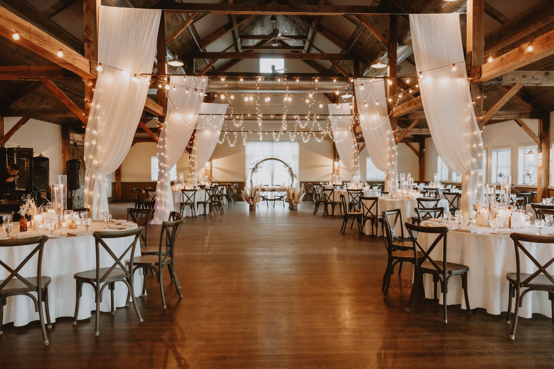 a room with tables and chairs and string lights by Mountain Hearts Photography
