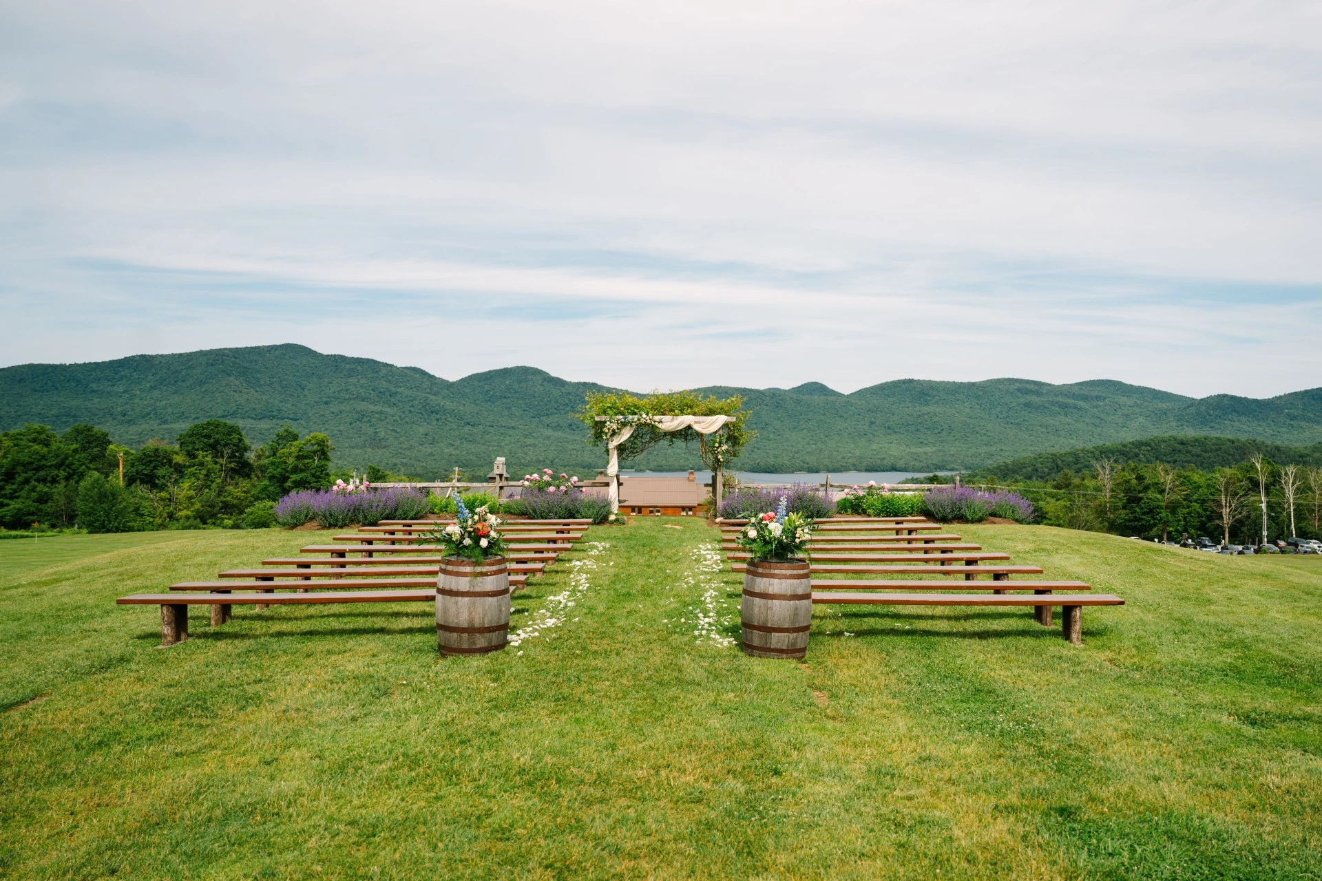 a wedding ceremony area with benches and barrels