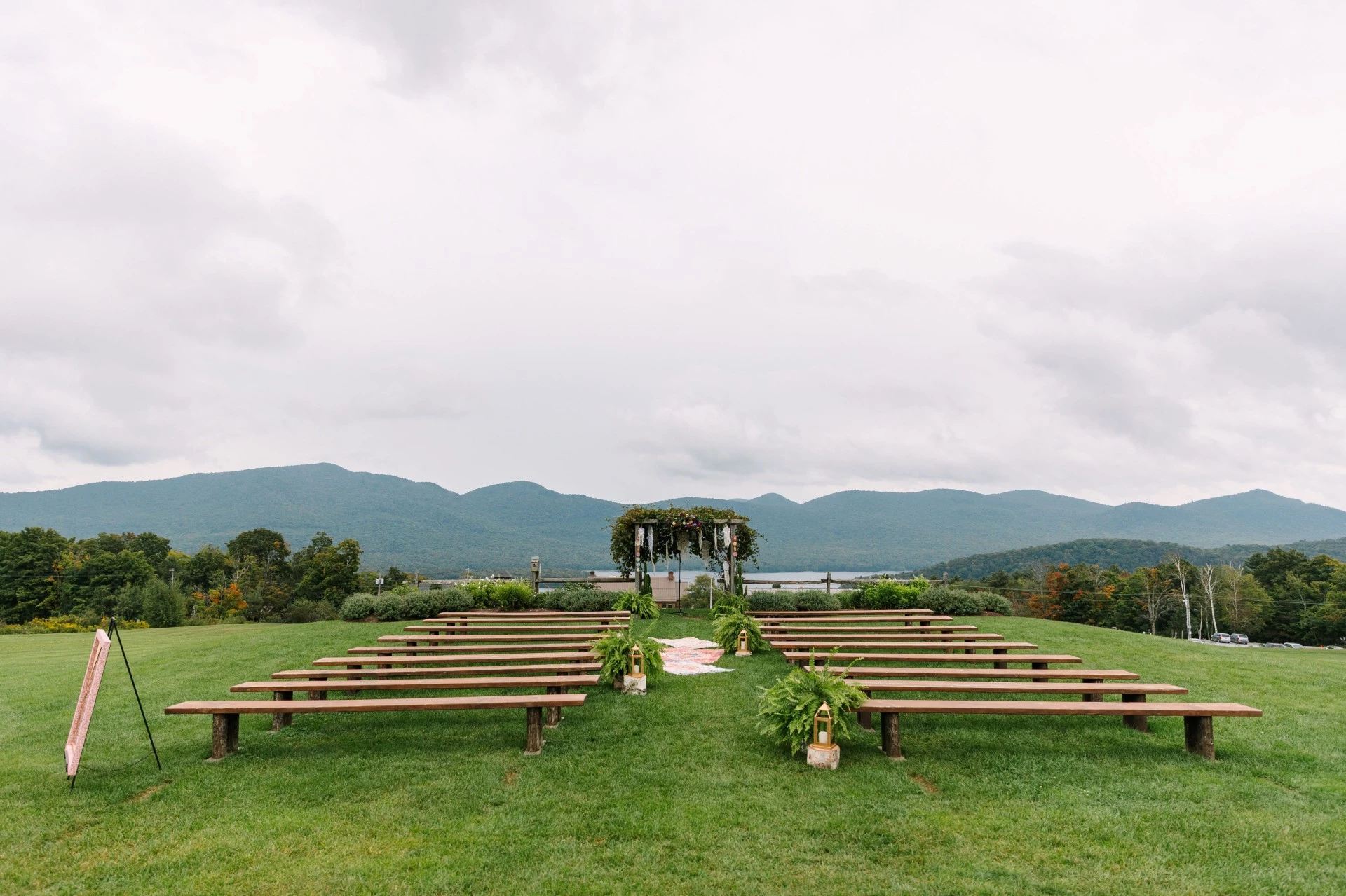 a wedding ceremony set up in a grassy area with benches and a white arch