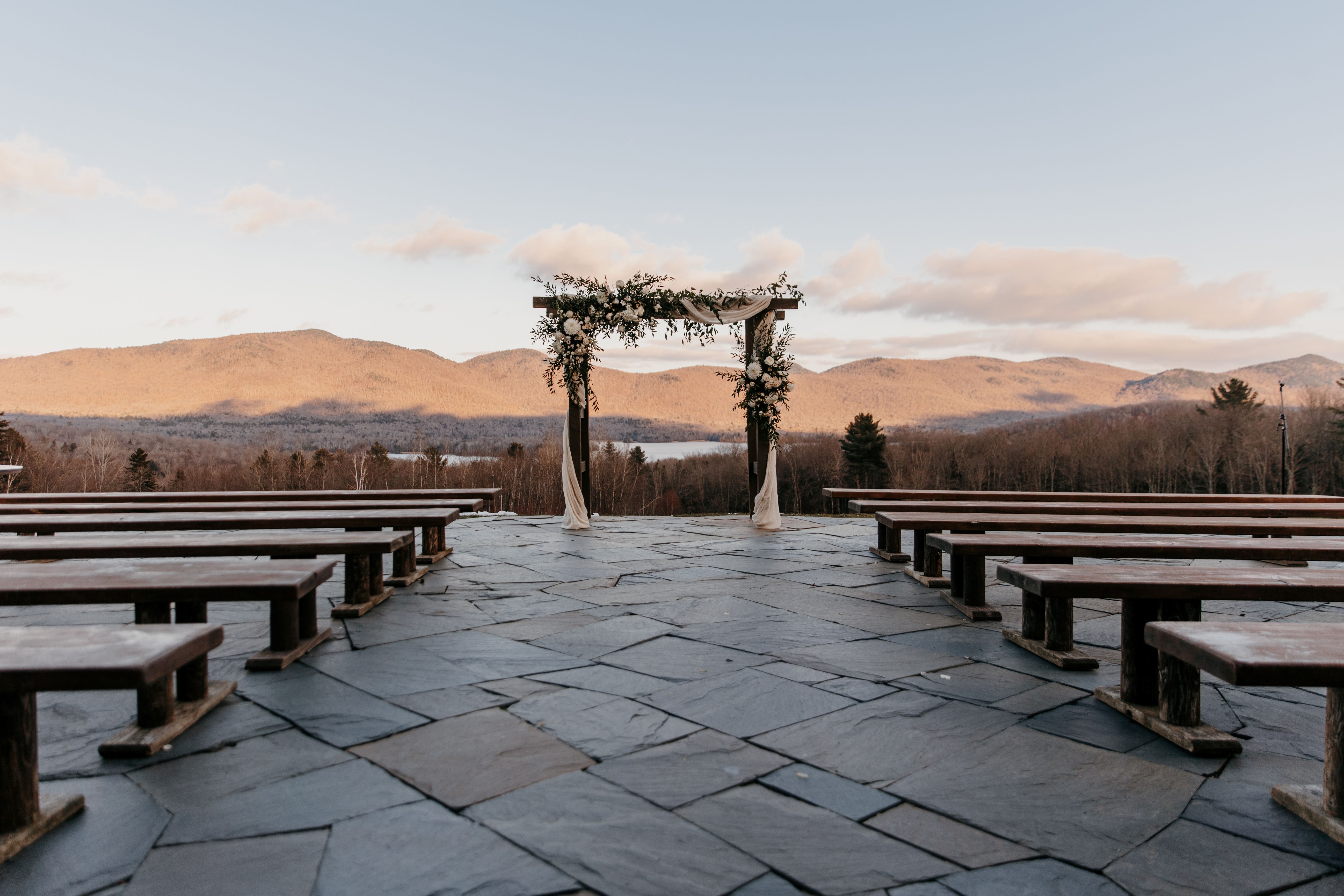 a group of benches on a stone patio with a view of mountains in the background