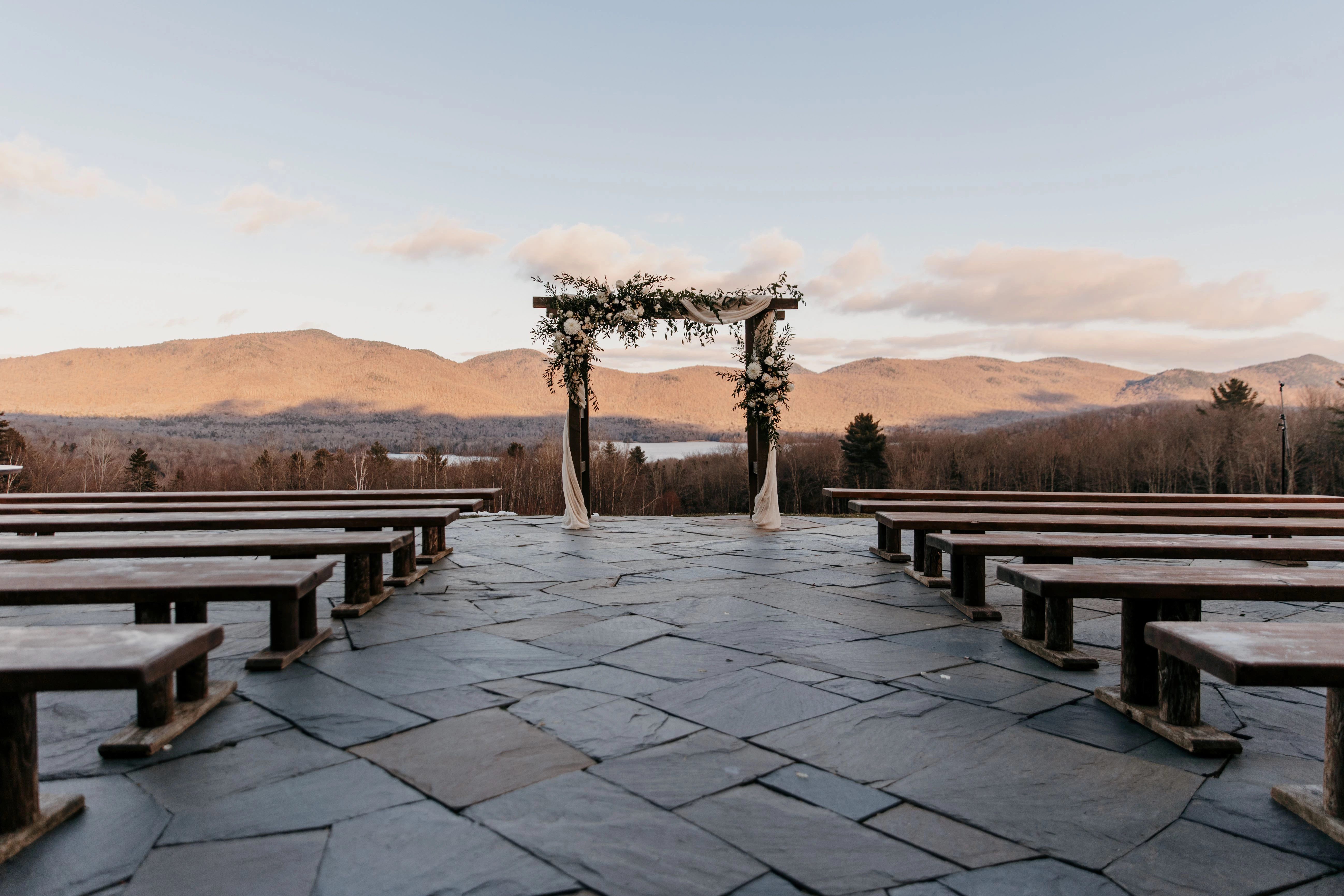 a group of benches on a stone patio with a view of mountains in the background