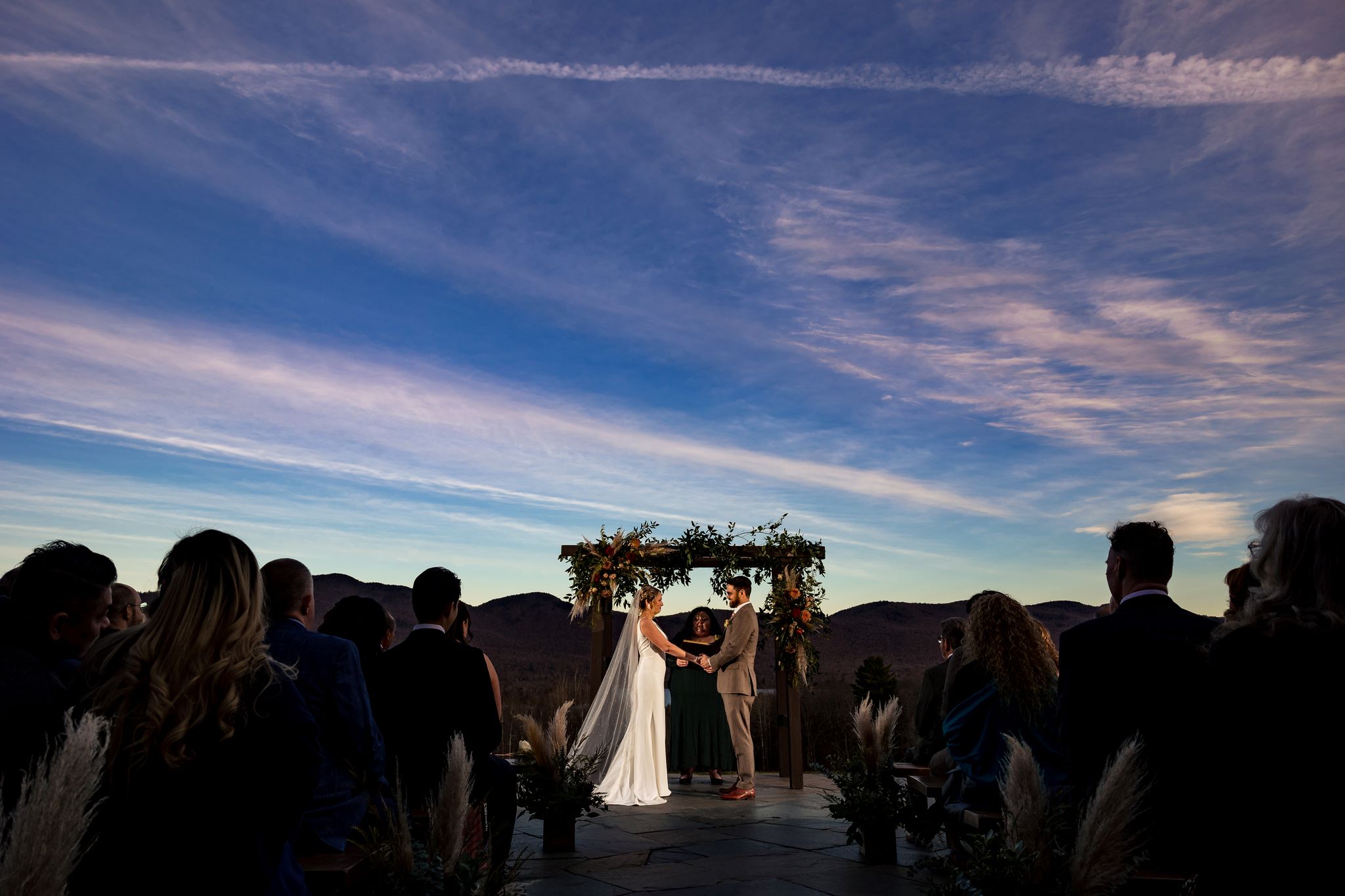 a couple in wedding attire under an arch with people watching