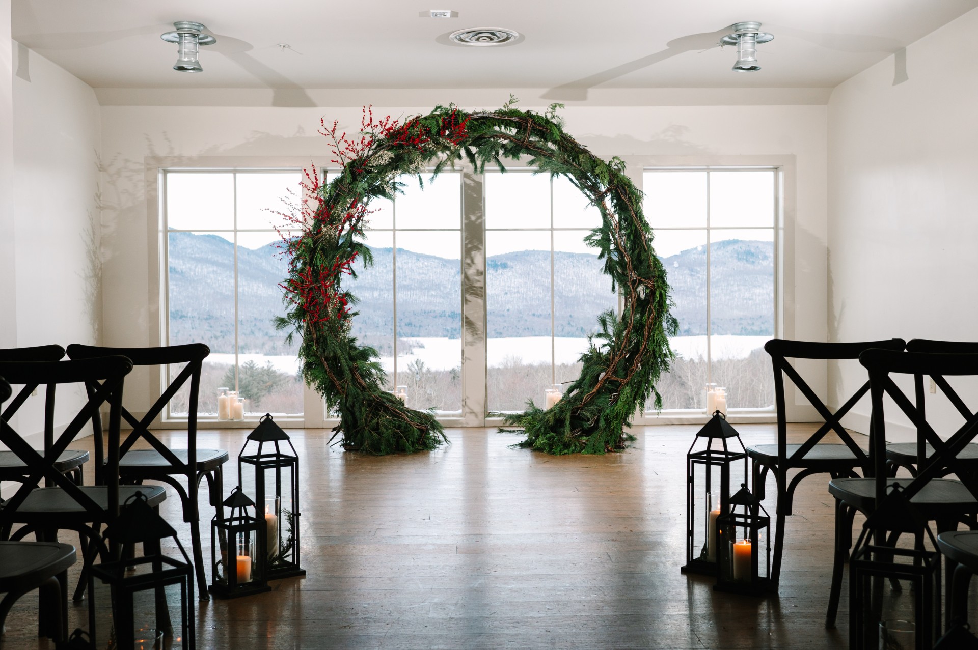 a large round arch in a room with windows and candles photographed by Juniper Studios