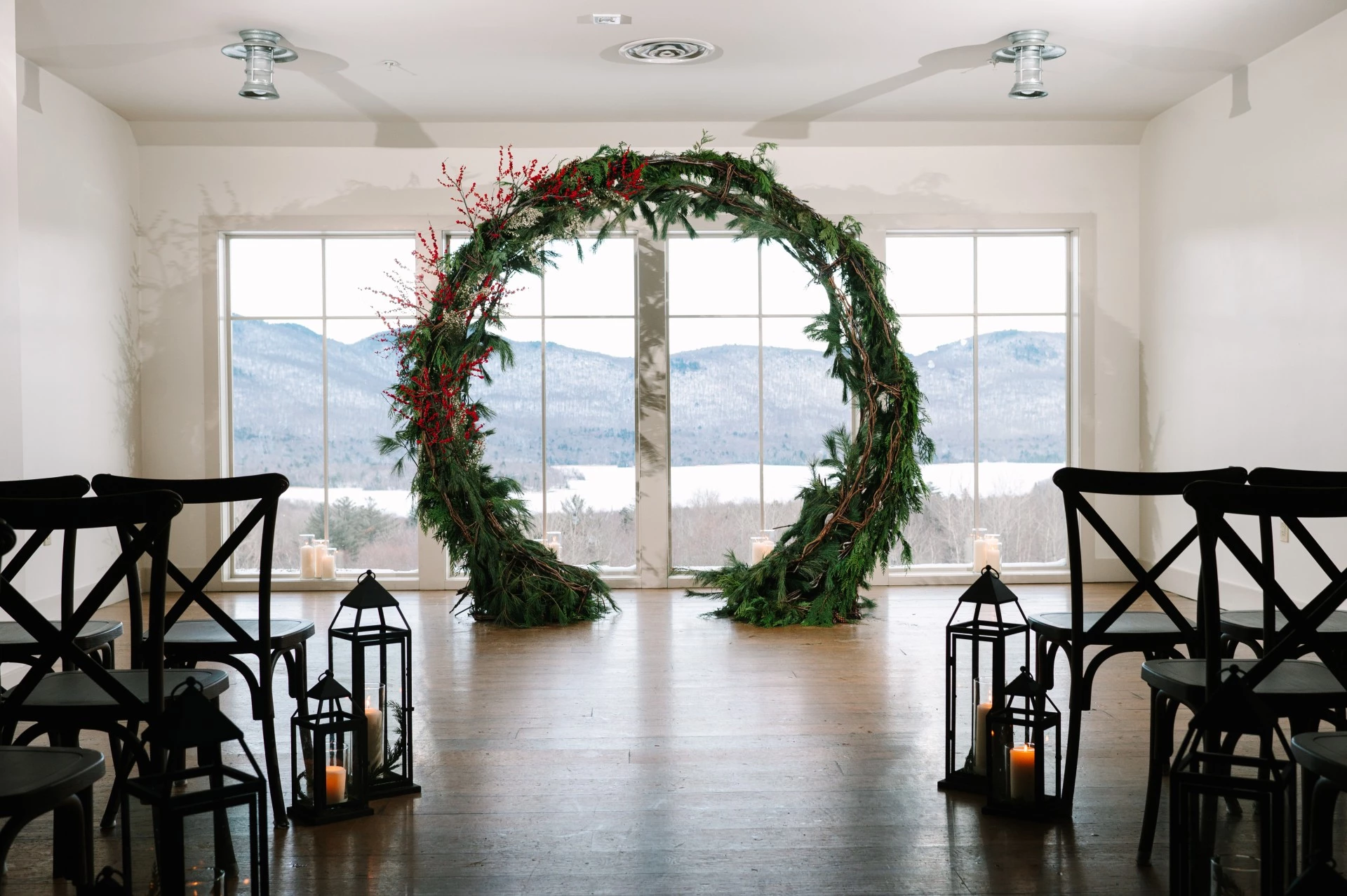 a large round arch in a room with windows and candles photographed by Juniper Studios