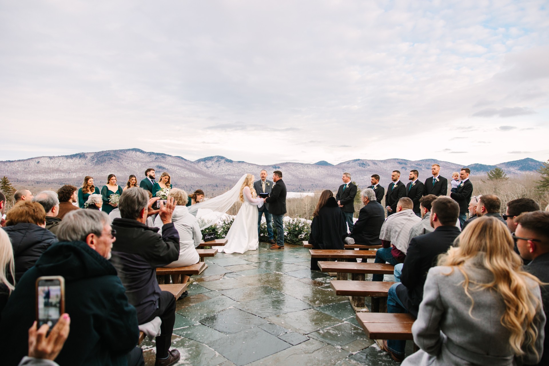 a bride and groom under a veil in front of a group of people by Juniper Studios
