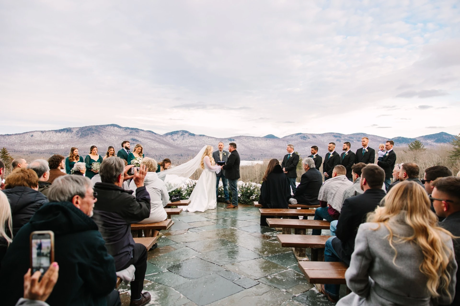 a bride and groom under a veil in front of a group of people by Juniper Studios