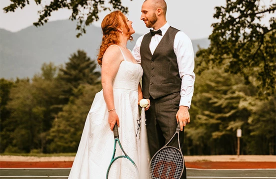 a man and woman holding tennis rackets and ball on a tennis court