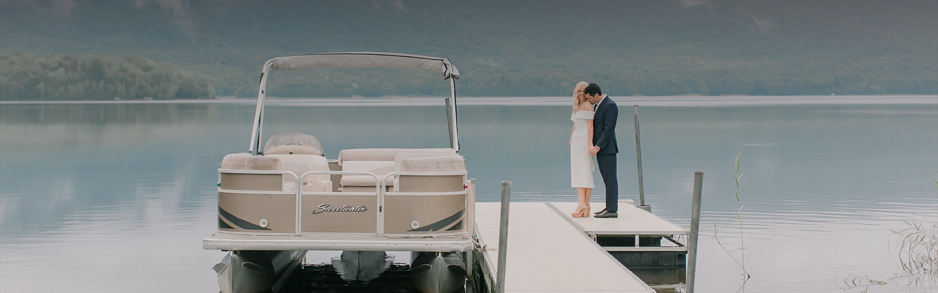 a man and woman kissing on a dock near a boat