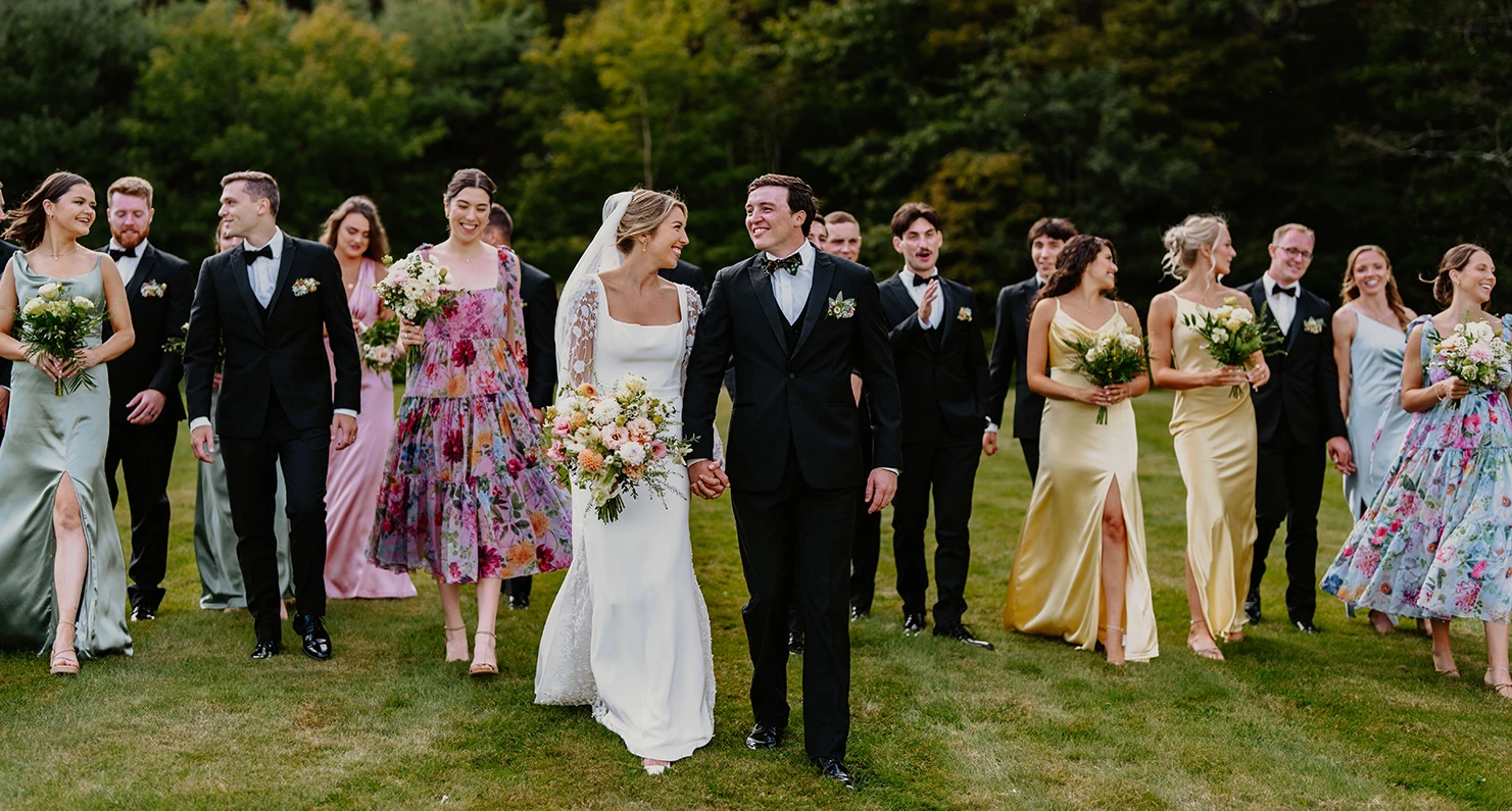a man and woman walking on grass with other people