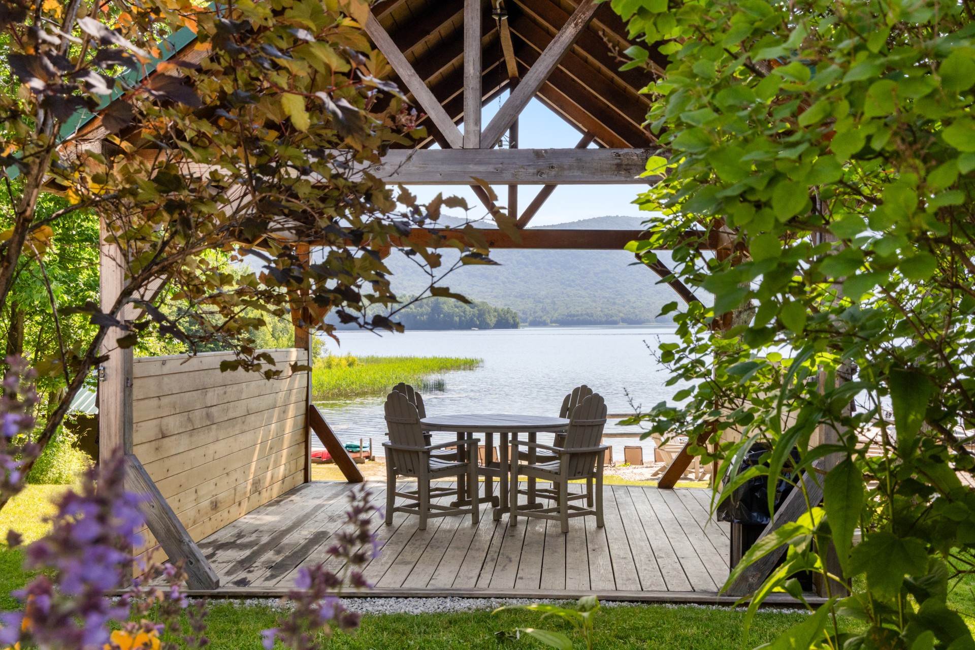 a wooden deck with chairs and a table on a lake