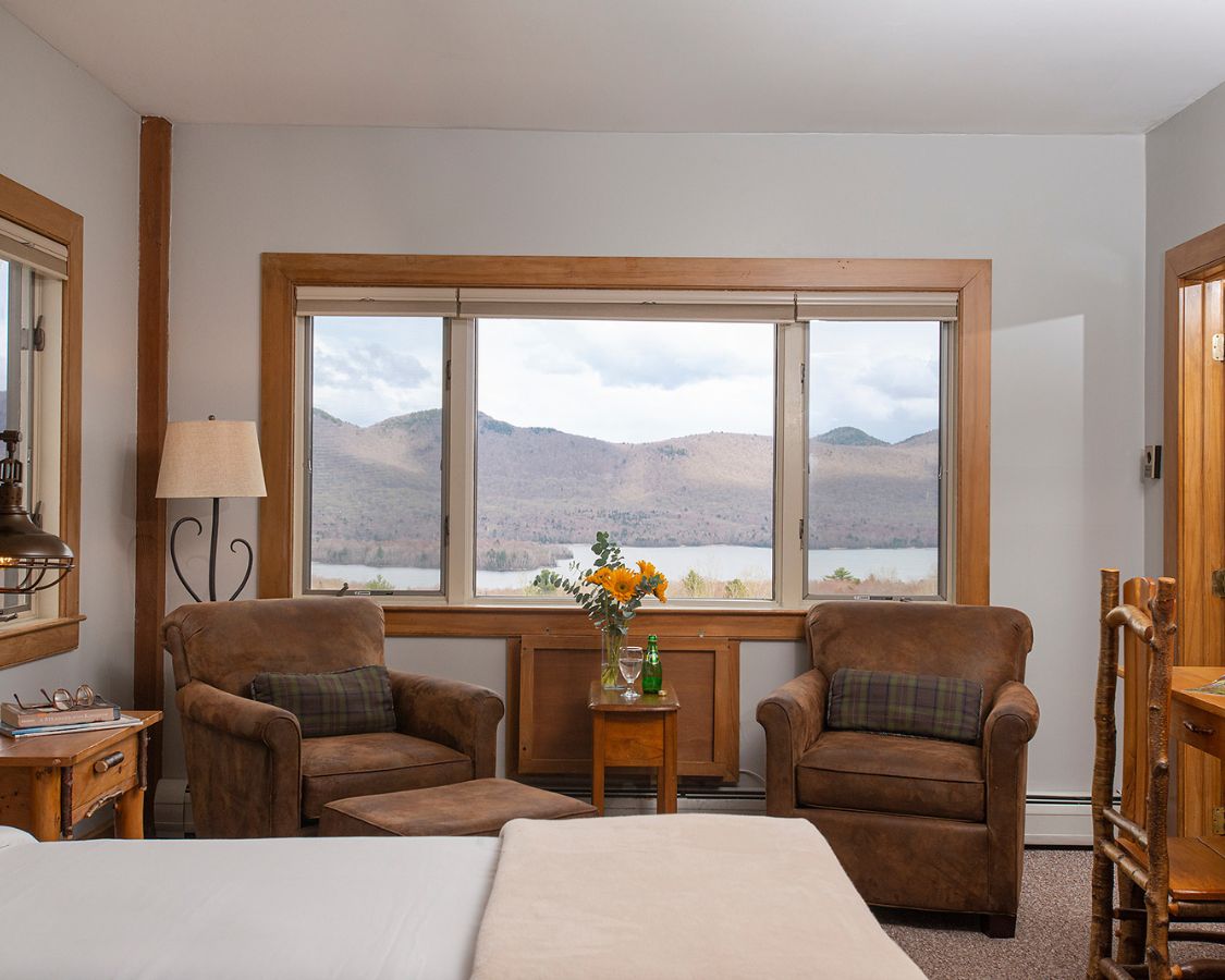 a room with a bed and chairs and a table with flowers