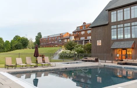 a pool with chairs and a fence in front of a building