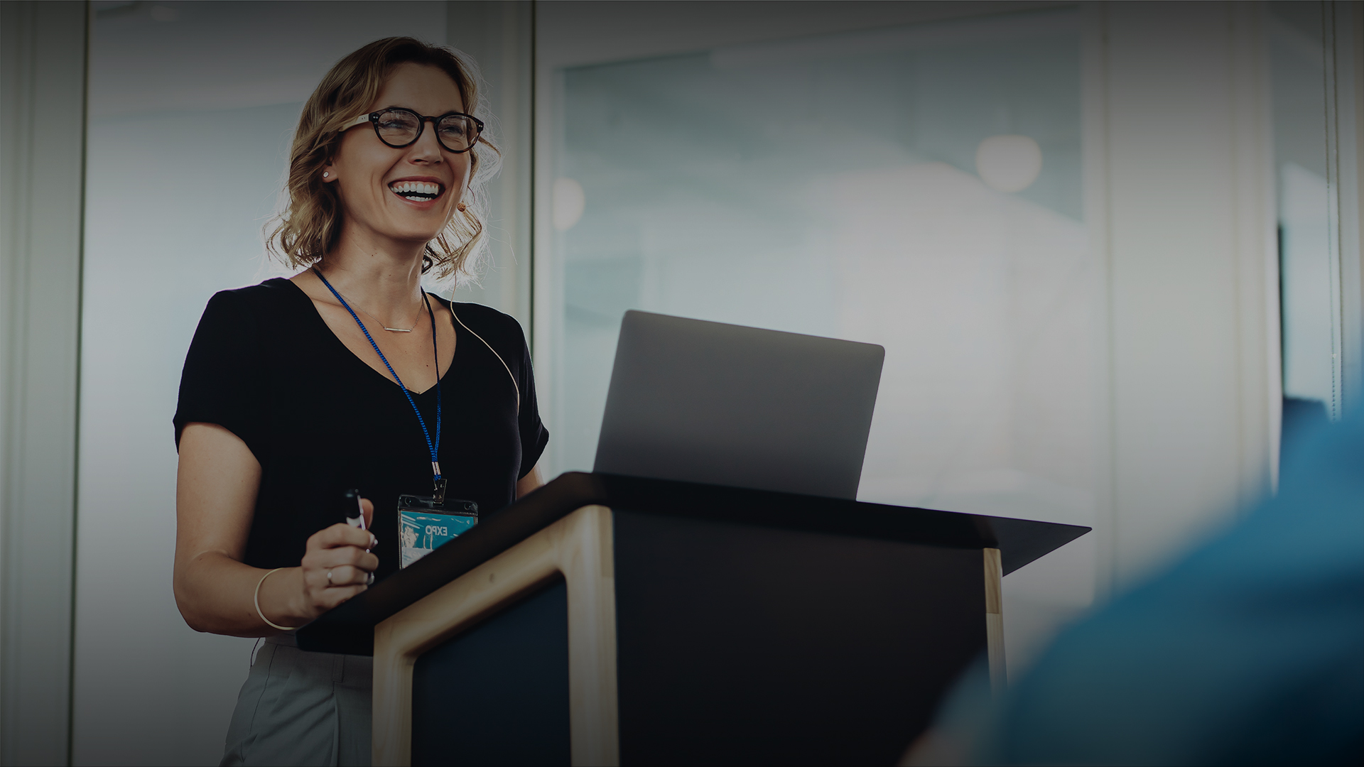 a woman standing at a podium with a laptop