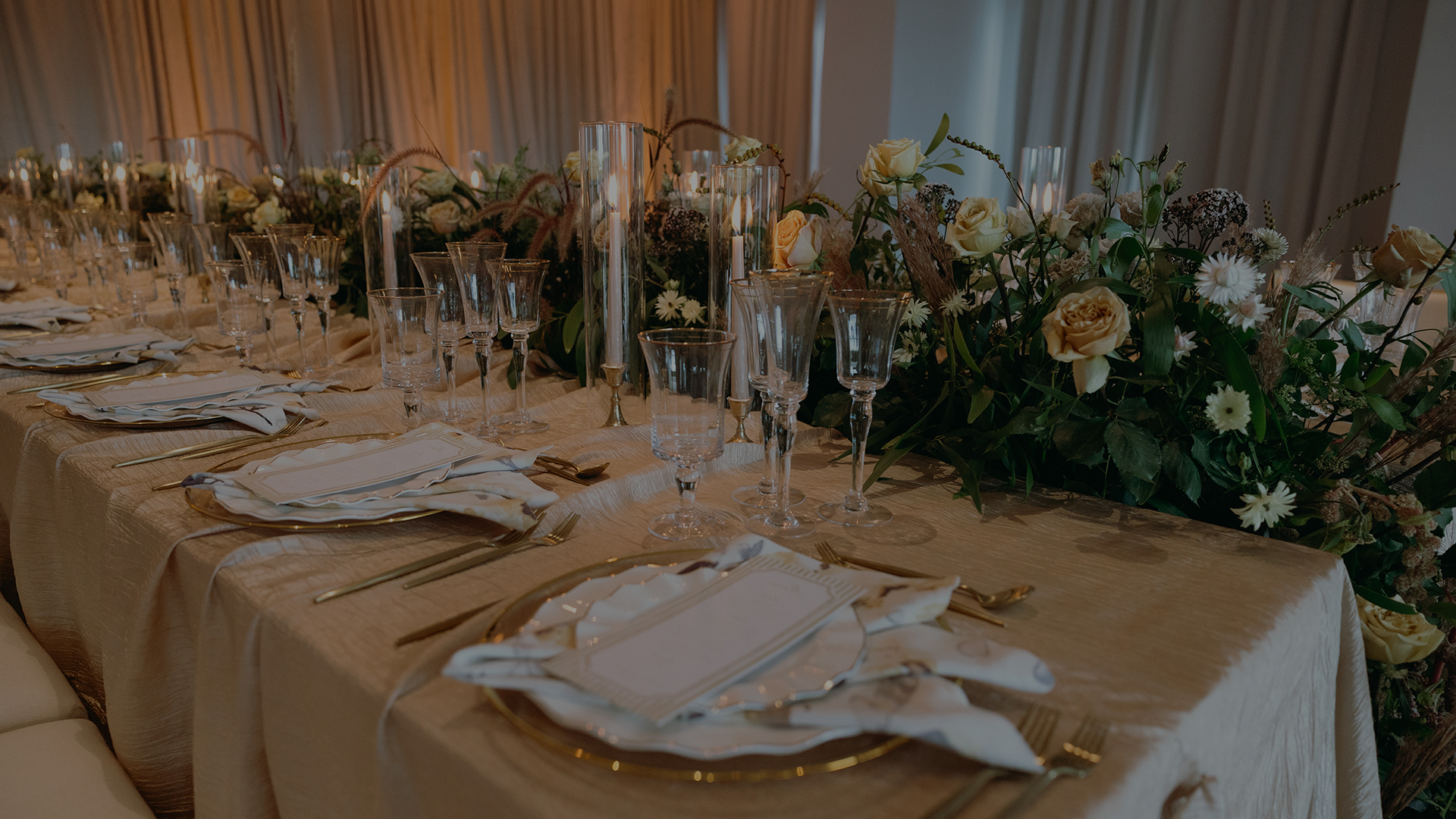 a table set with glasses and plates and flowers