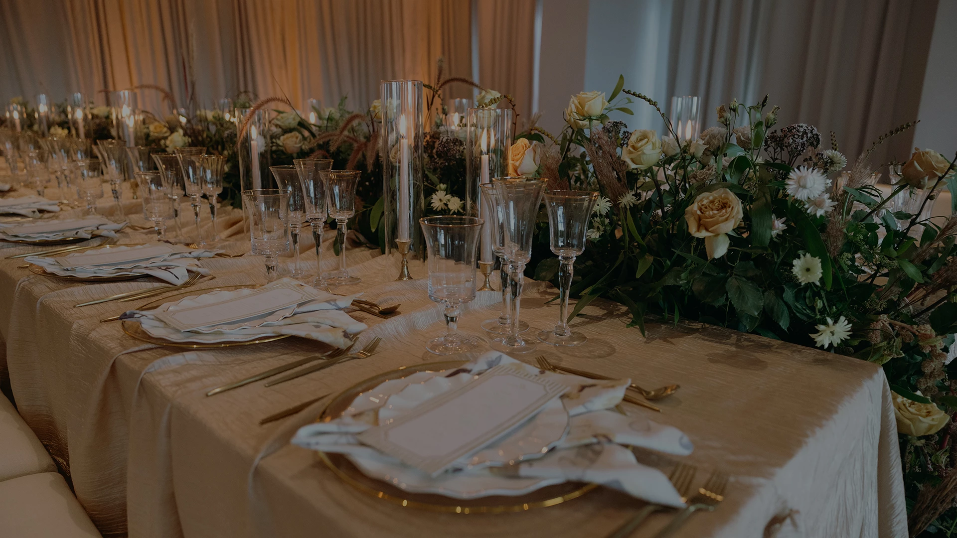 a table set with glasses and plates and flowers