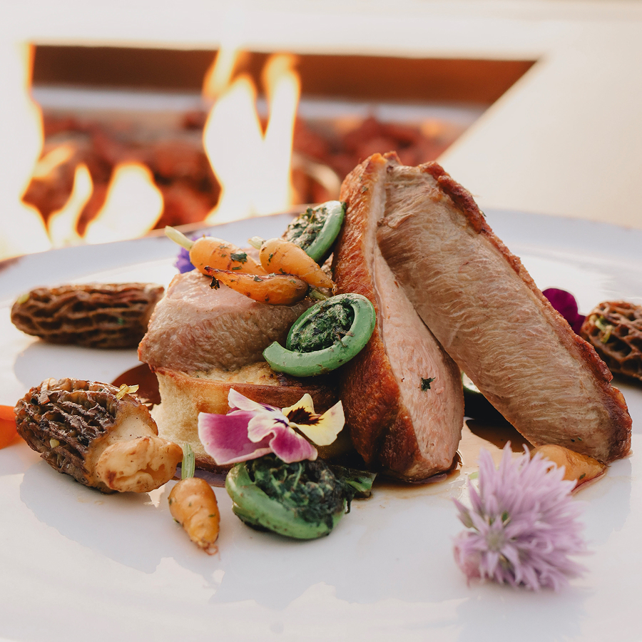 a plate of food with flowers and a fire in the background