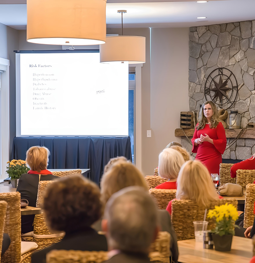 a woman in a red dress giving a presentation to a group of people