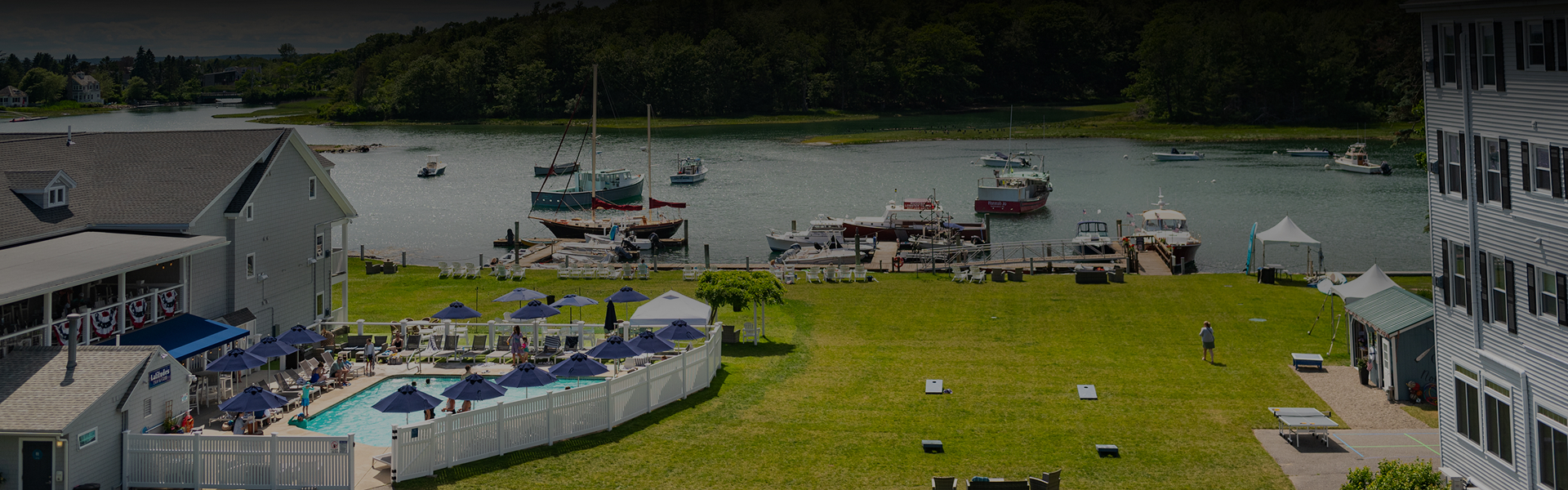 a body of water with boats and a dock with umbrellas and a white fence
