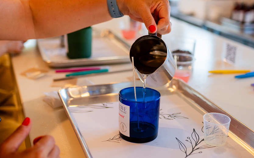 a person pouring liquid into a blue candle