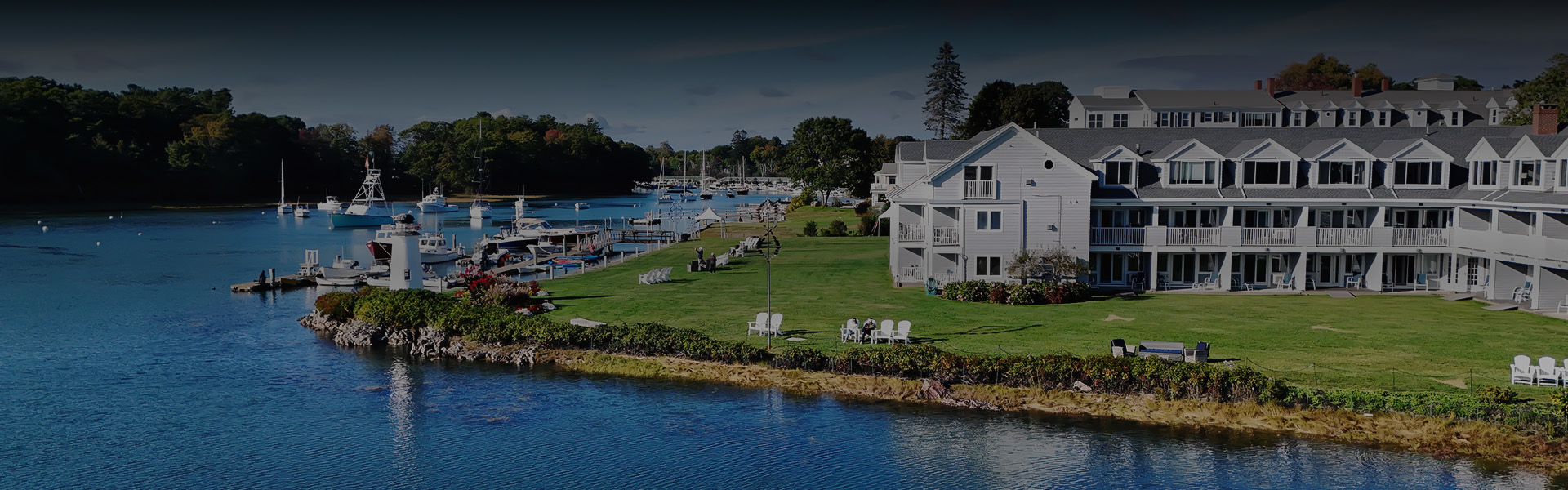 a white house with lawn and boats in the water