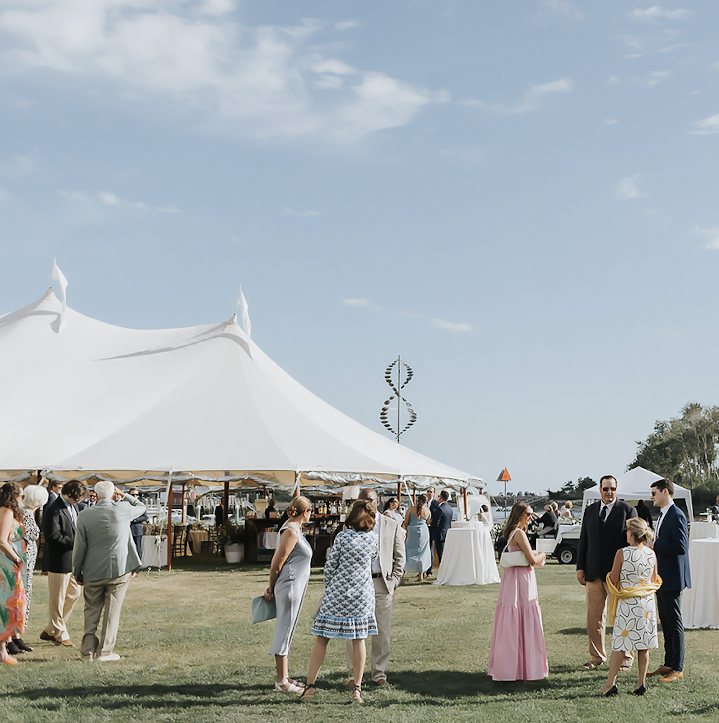 a group of people standing in front of a white tent