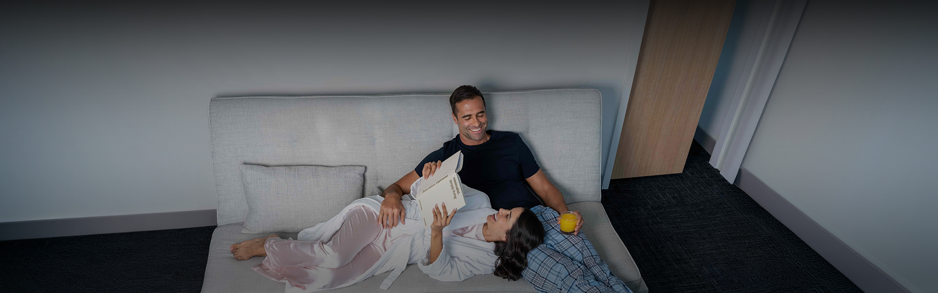 a man and woman lying on a couch reading a book