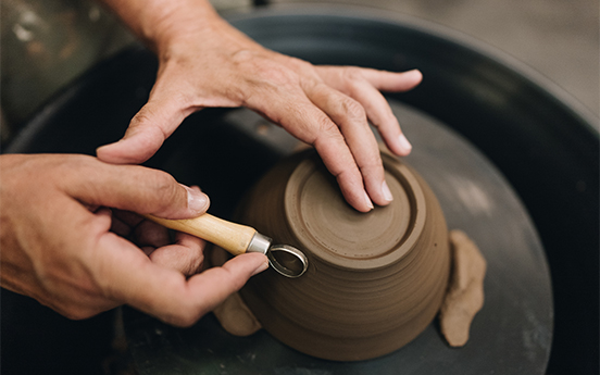 a person's hands working on a clay bowl