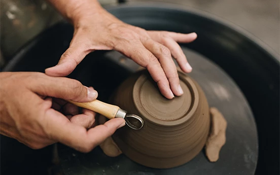a person's hands working on a clay bowl