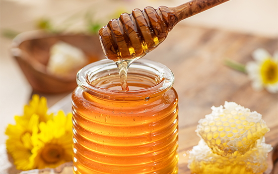 a honey dipper over a jar of honey