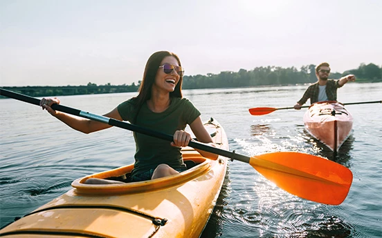 a woman in a kayak with a man in the background