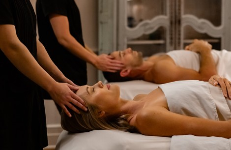 a man and woman lying on bed with hands on head