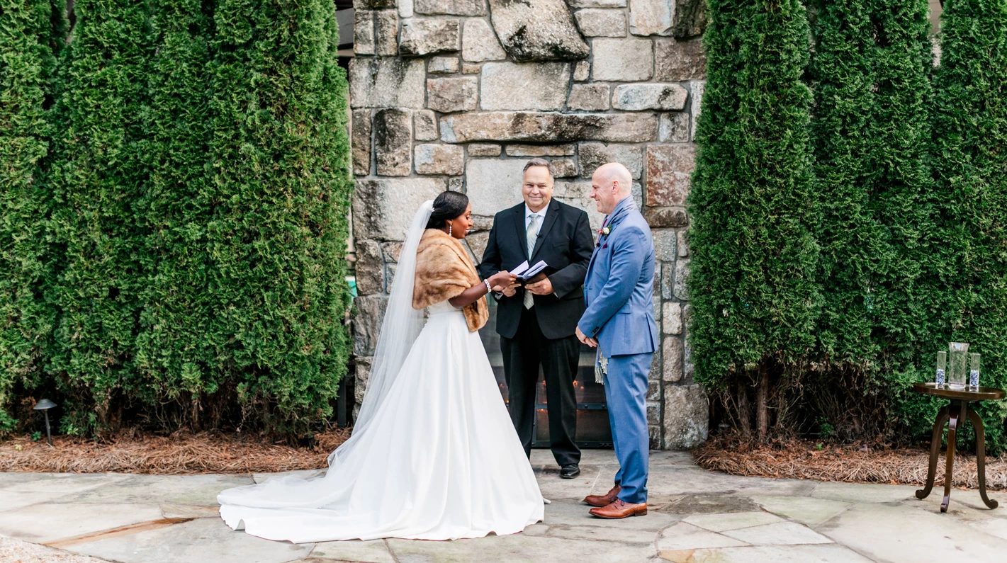 a bride and groom standing in front of a stone wall
