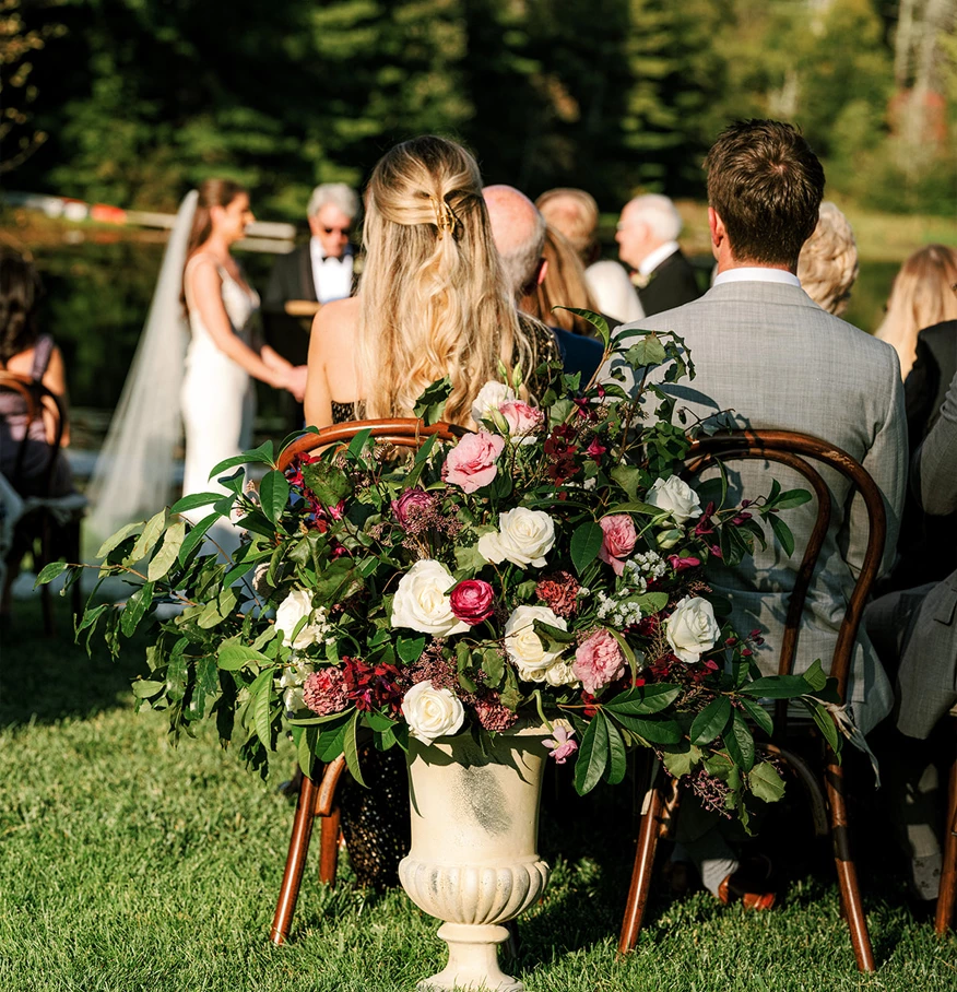 a group of people sitting in chairs with a vase of flowers