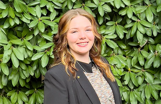 a woman smiling in front of a bush