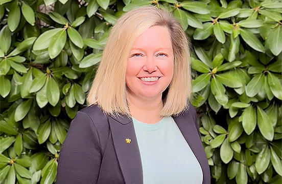 a woman smiling in front of a bush