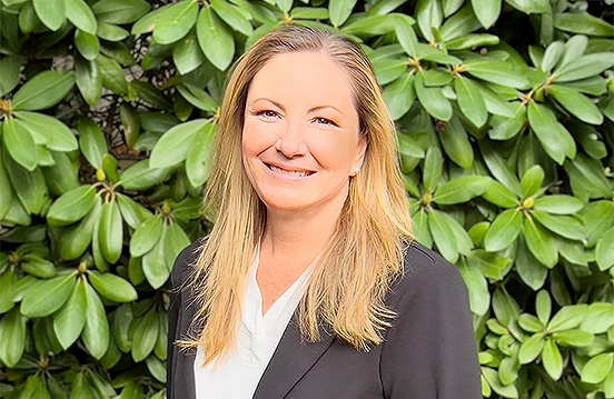 a woman smiling in front of a bush