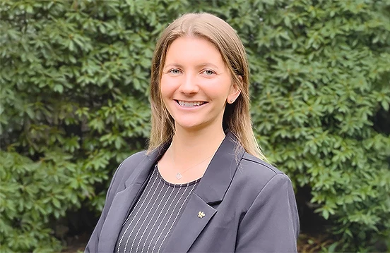 a woman smiling in front of a bush