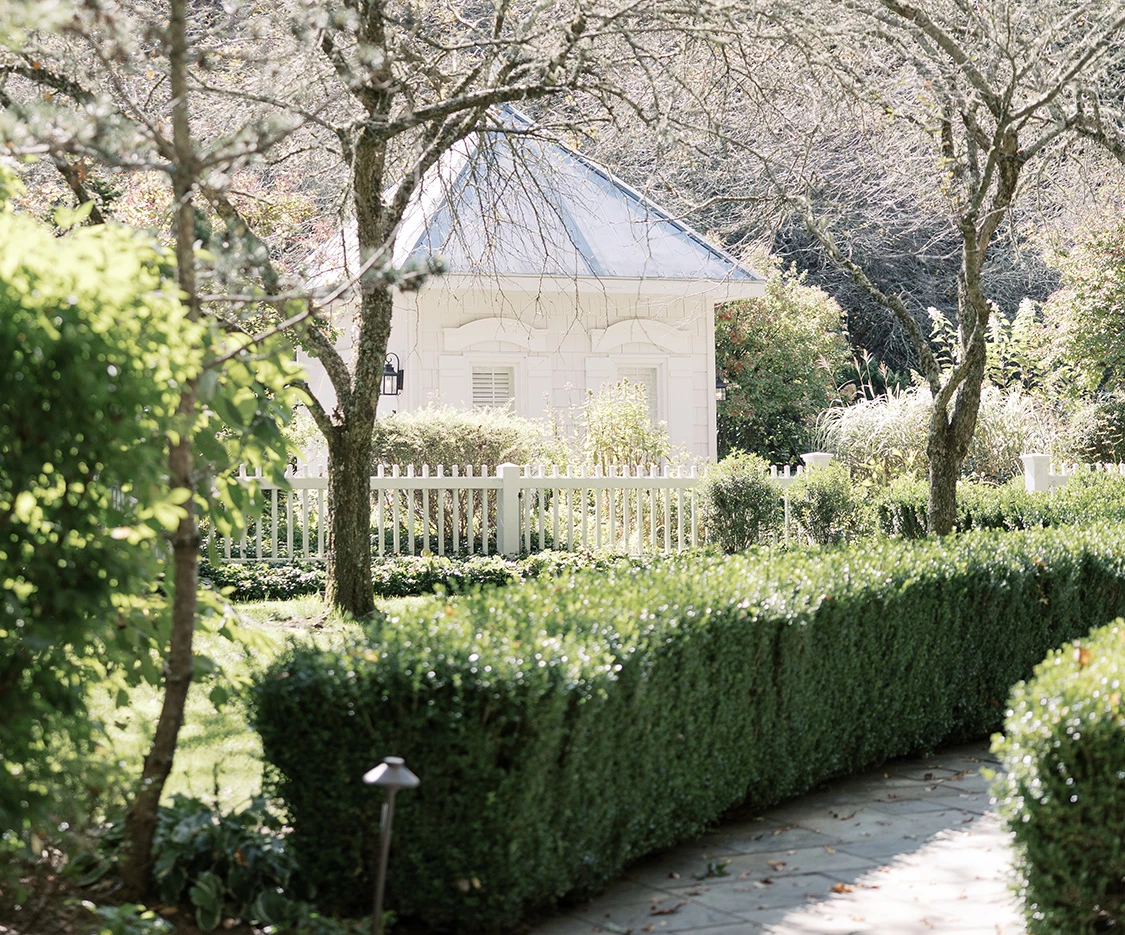 a white house with a white picket fence and bushes