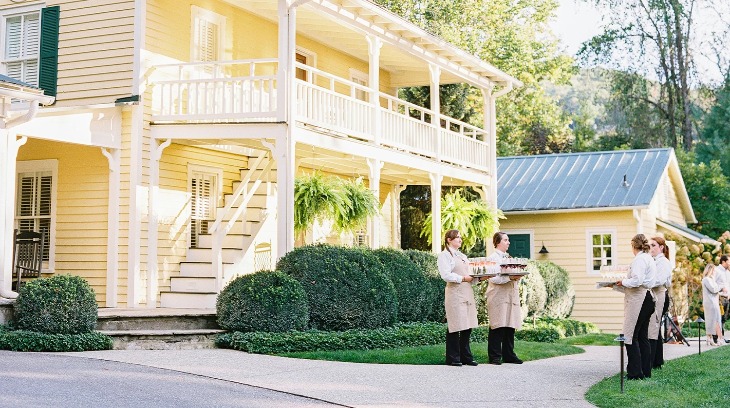 two women carrying food in front of a house