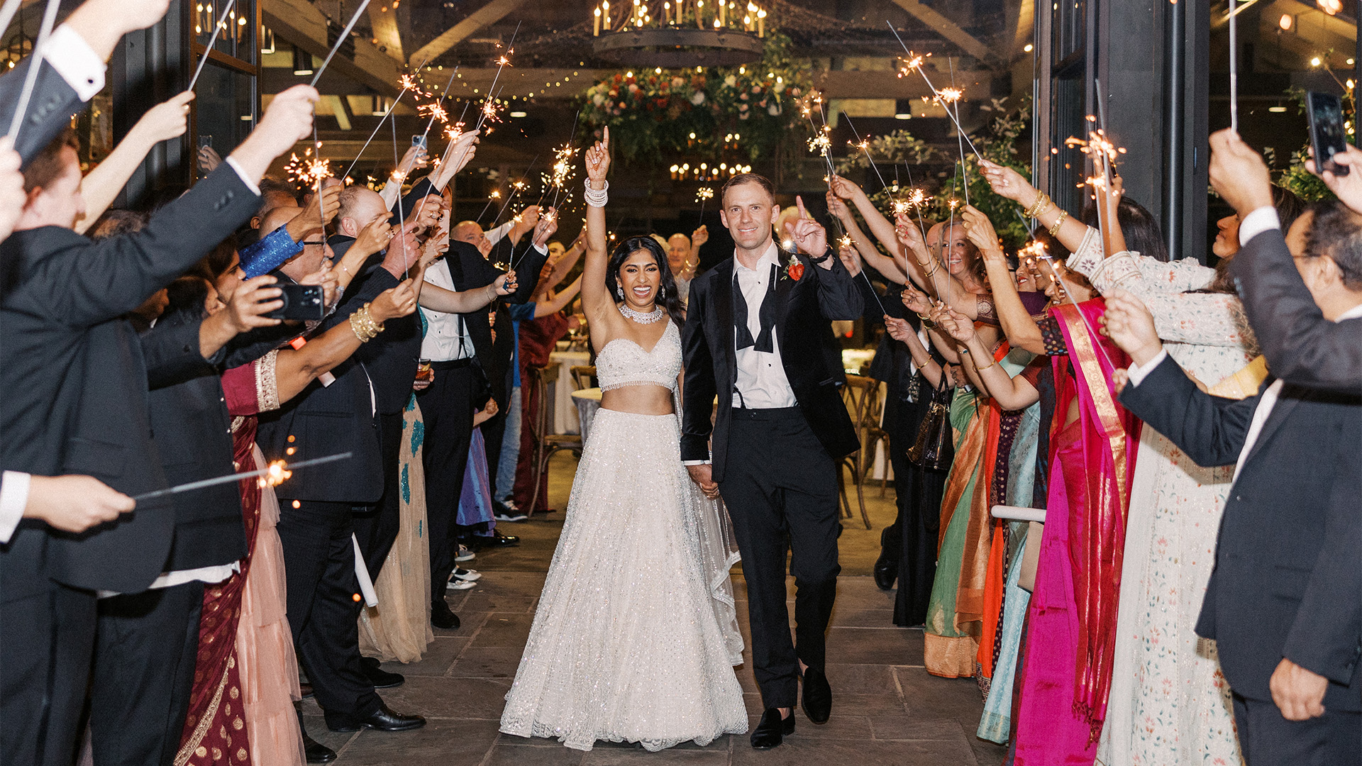 a man and woman walking down a walkway with sparklers