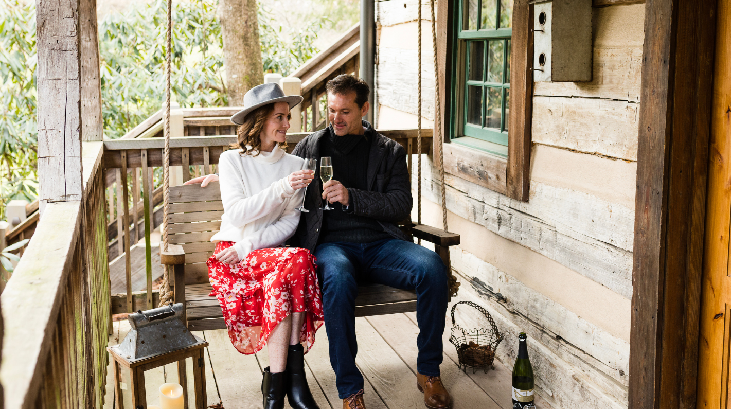 a man and woman sitting on a swing with wine glasses