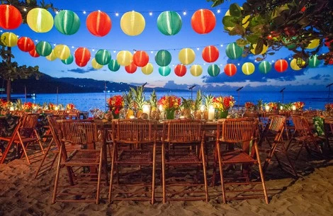 a table set up with colorful lanterns and a beach in the background