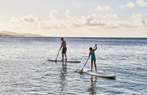 a man and woman on paddle boards in the water